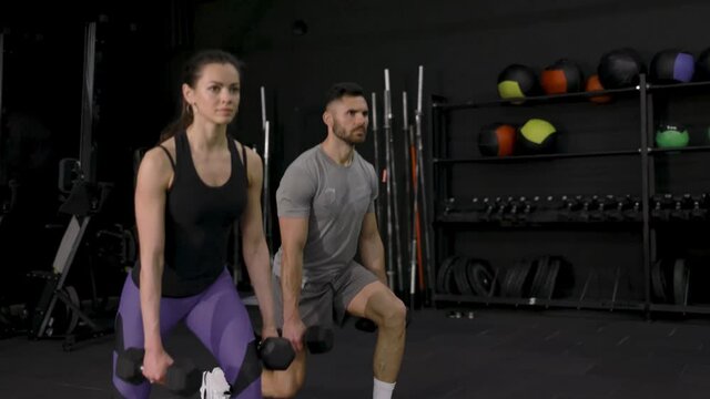 Fitness couple in sportswear doing lunges exercises at gym.