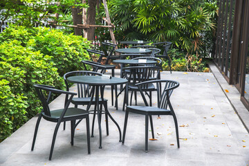 Black chairs and round tables set in the garden at a cafe, outdoor zone in Thailand, outside...
