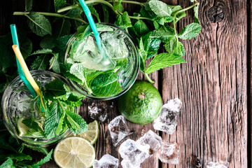 Mojito cocktails ingredients background. Two glasses with a natural mojito cocktail on a wooden rustic background.