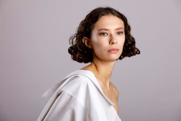 Fototapeta premium Portrait of a young woman with an elegant hairstyle and a long neck on a light background.