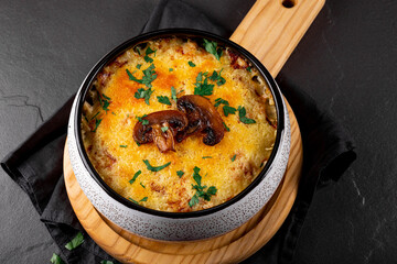 Julienne with potatoes and mushrooms in a baking dish on a dark background, close up. Traditional French dish