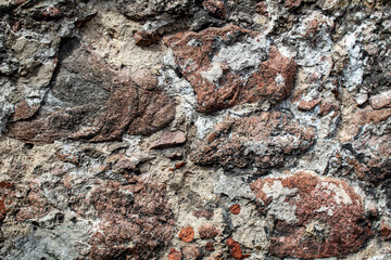 Fragment of the wall of the old house, stone masonry made of natural granite.