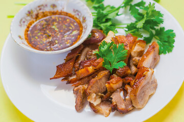 Grilled pork mask was marinated with minced coriander root, black pepper and garlic and served with Thai spicy sauce (Jaew sauce).