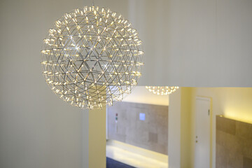 A modern gold colored metal chandelier in a white concrete room