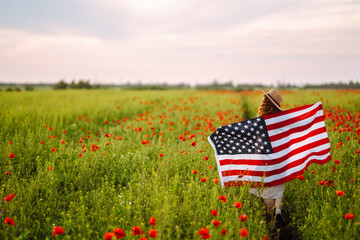 Young woman waves an american flag on the poppy field. United States of America independence day, 4th of July concept.