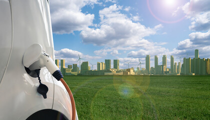 Close up of electric car with a connected charging cable on the background of green eco city