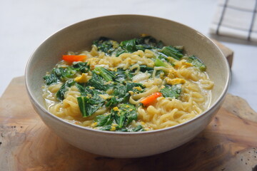 a bowl of noodle soup with vegetables in white background