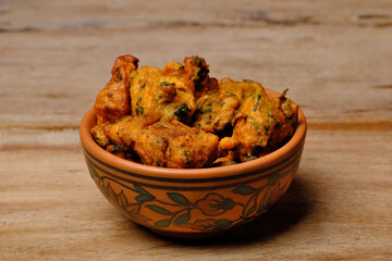Indian snack pakora in a bowl on wooden background