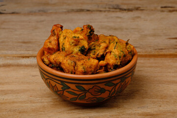 Indian snack pakora in a bowl on wooden background