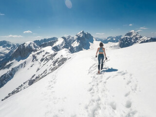 Fototapeta na wymiar slender positive girl climber mountaineer with ice axe on a snowy alpine slope