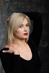 Fototapeta na wymiar Young blonde plump woman with bright makeup in black bodysuit at dark background