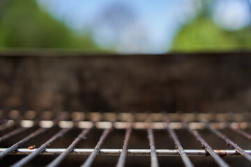 Empty dirty grill rust from the front. Depth perspective. Nature and sky in background.
