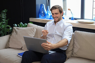 Fototapeta premium Smiling businessman greeting colleagues in video conference and negotiating distantly from home.