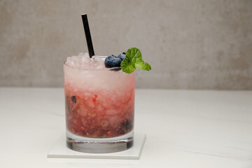 Blueberry mojito cocktail with blueberries, lime, mint and ice in glass on gray background. Summer cold alcoholic non-alcoholic drinks, beverages and cocktails. Front view with copy space.