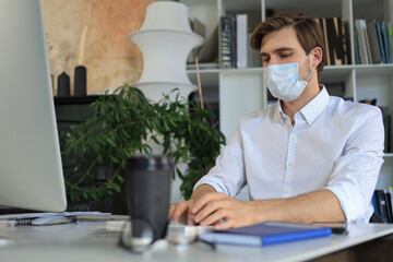 Fototapeta na wymiar Businessman is working in preventive medical mask in office.
