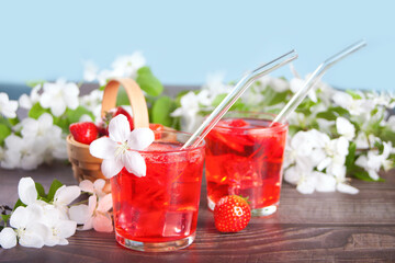 Strawberry cold refreshment lemonade with ice cube. White apple blossoms on the background. Spring concept.