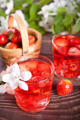 Strawberry cold refreshment lemonade with ice cube. White apple blossoms on the background. Spring concept.