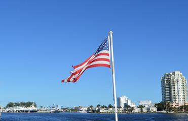 American Flag flying in the background of Fort Lauderdale Canals and city skyline on a sunny summer day.
