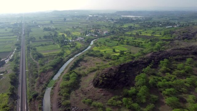 Aerial footage of a mainline Electric Multiple Unit or MEMU train of the Indian Railways at Uruli near Pune India.