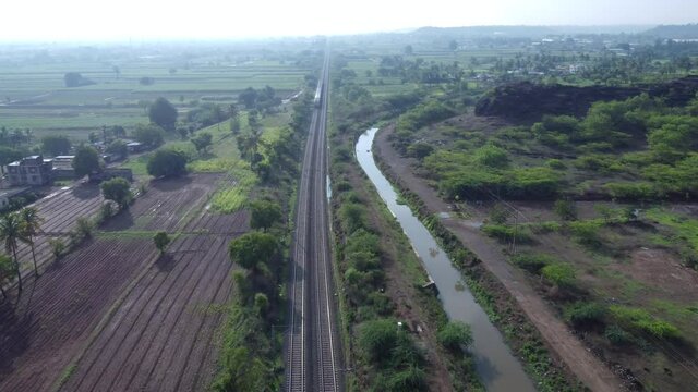 Aerial footage of a mainline Electric Multiple Unit or MEMU train of the Indian Railways at Uruli near Pune India.