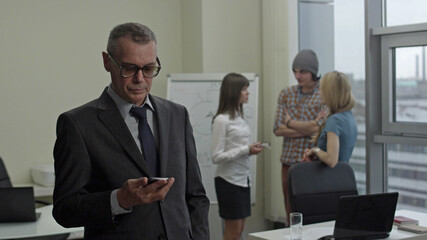 Portrait of maturebusinessman in modern office using smartphone