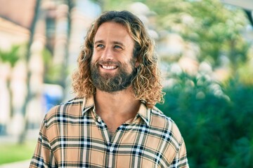 Young caucasian man with long hair smiling happy at the park.