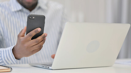 Close Up of African Man using Smartphone and Laptop 
