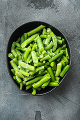 Green beans. Fresh frozen beans for salad, cooking or raw vegan food, in bowl, on gray stone background, top view flat lay