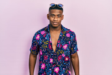 Young black man wearing hawaiian shirt and sunglasses with a happy and cool smile on face. lucky person.