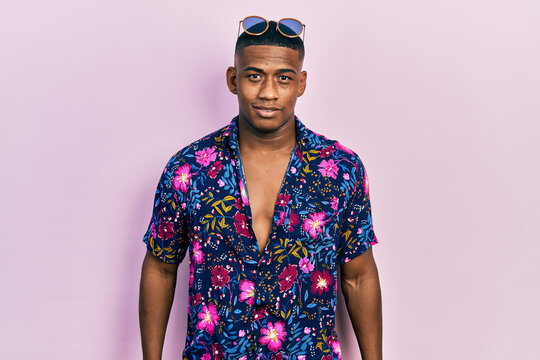 Fototapeta Young black man wearing hawaiian shirt and sunglasses with a happy and cool smile on face. lucky person.