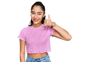 Hispanic teenager girl with dental braces wearing casual clothes smiling doing phone gesture with hand and fingers like talking on the telephone. communicating concepts.