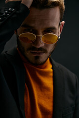 Obraz premium a brutal guy with glasses and a black jacket orange sweater dark background 
