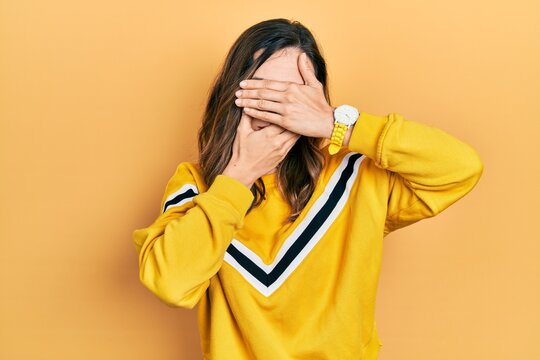 Young hispanic girl wearing casual clothes covering eyes and mouth with hands, surprised and shocked. hiding emotion