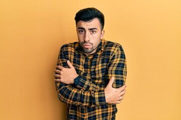 Young hispanic man wearing casual clothes shaking and freezing for winter cold with sad and shock...