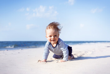 happy, smiling boy on the beach. 8 month old blond boy crawling on the beach