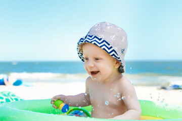 Cute boy playing with beach toys in the kids pool on the beach. eight month old blond boy