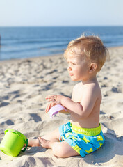 Cute baby boy playing with beach toys on beach. eight-month old blond boy