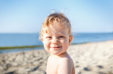 portrait of a happy, smiling boy on the beach. eight month old blond boy