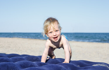 happy smiling boy on the beach.10 month old blond boy