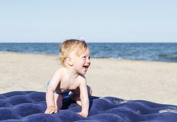 happy smiling boy on the beach.10 month old blond boy