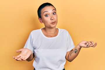 Beautiful hispanic woman with short hair wearing casual white t shirt clueless and confused...