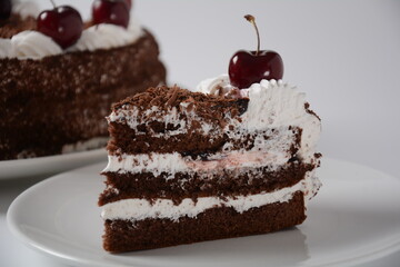 Black forest cake, Schwarzwald pie, dark chocolate and cherry dessert on a white background. Black forest cake decorated with whipped cream and cherries.