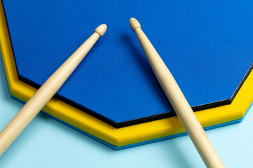 Drum sticks and training mat on a blue background