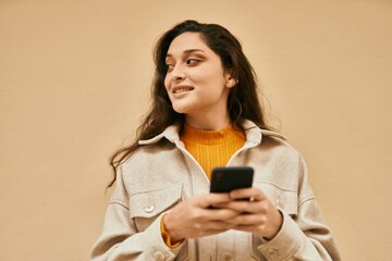 Young middle east woman smiling happy using smartphone at the city.