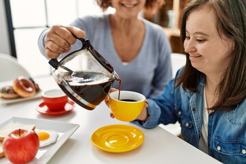 Mature mother and down syndrome daughter having coffee and lunch at home