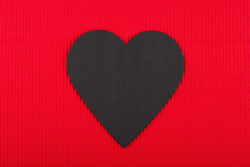 Top view of black paper heart on red background. Concept of love, Valentine's day and relationship