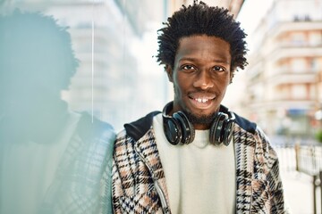 Handsome black man with afro hair wearing headphones smiling happy outdoors