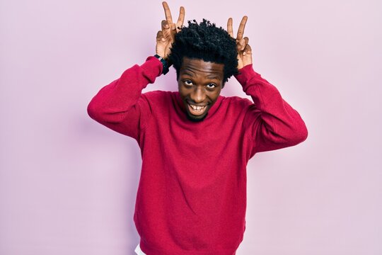 Young african american man wearing casual clothes posing funny and crazy with fingers on head as bunny ears, smiling cheerful