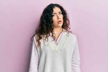 Fototapeta premium Young brunette woman with curly hair wearing casual clothes in shock face, looking skeptical and sarcastic, surprised with open mouth