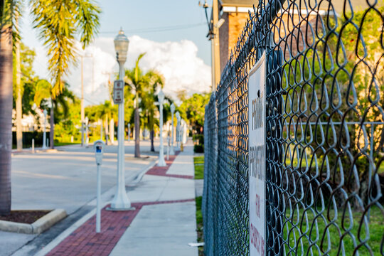 View down a sidewalk in downtown area with bricks and a fence showing private property.